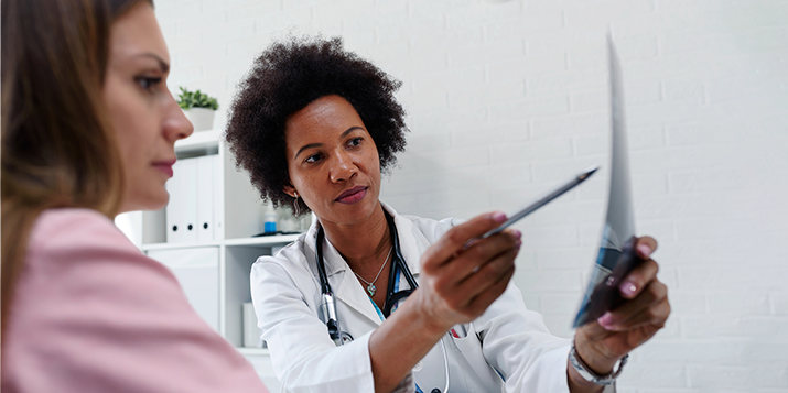 Une médecin présente un document à une patiente pour lui fournir de l’information.
