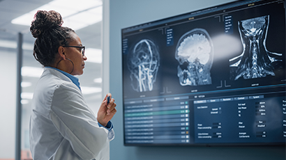 Une femme portant un sarrau examine des images médicales sur un écran