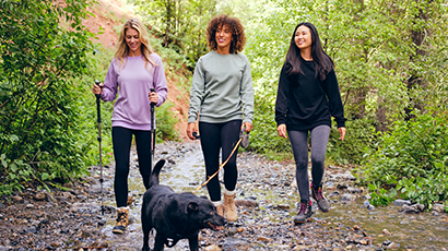 Trois femmes promener un chien le long d'un chemin boisé