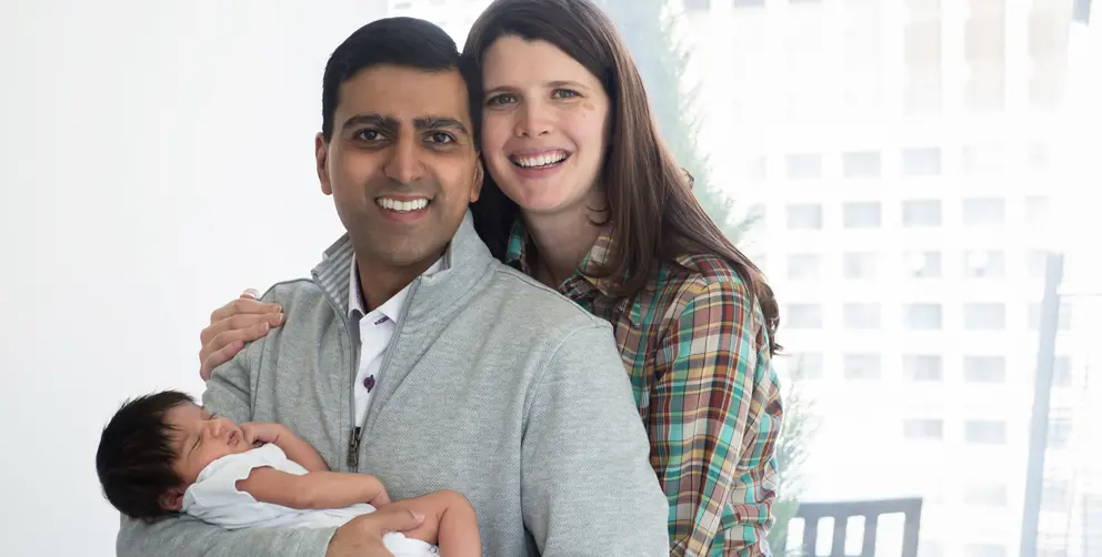 Irfhan Rawji et son épouse Christine, unis avec Zain, leur nouveau-né, dans les bras, sourient pour la photo.