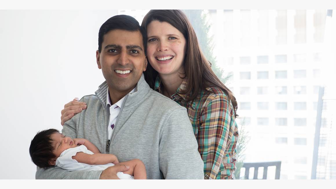 Irfhan Rawji et son épouse Christine, unis avec Zain, leur nouveau-né, dans les bras, sourient pour la photo.