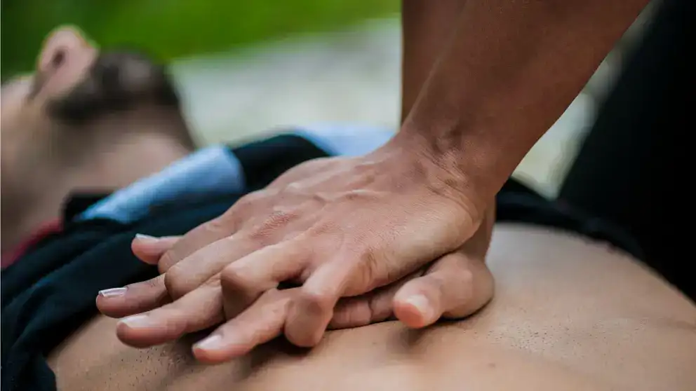 Une personne effectue des compressions thoraciques sur la poitrine d’une personne en arrêt cardiaque.