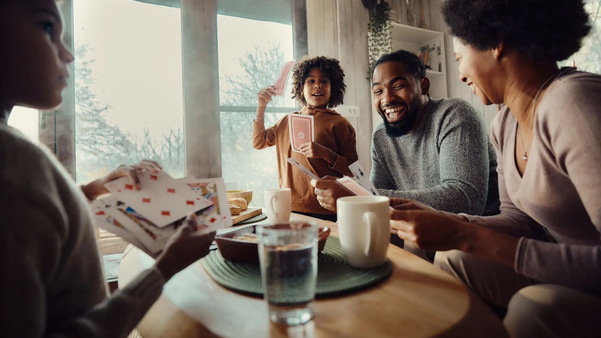 Une famille jouant aux cartes autour d’une table.