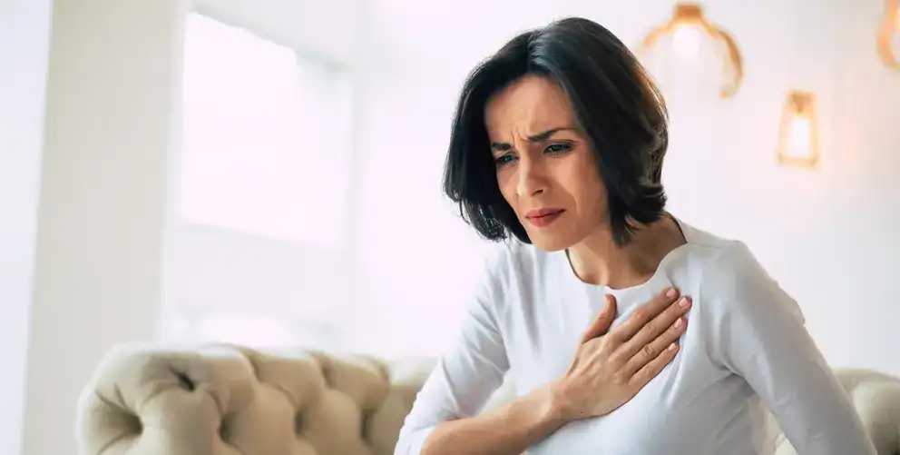 Une femme porte la main à son cœur en proie à un inconfort.