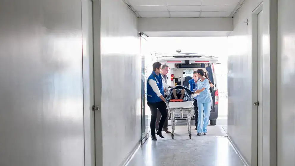  Une équipe médicale pousse un patient sur une civière dans un hôpital.