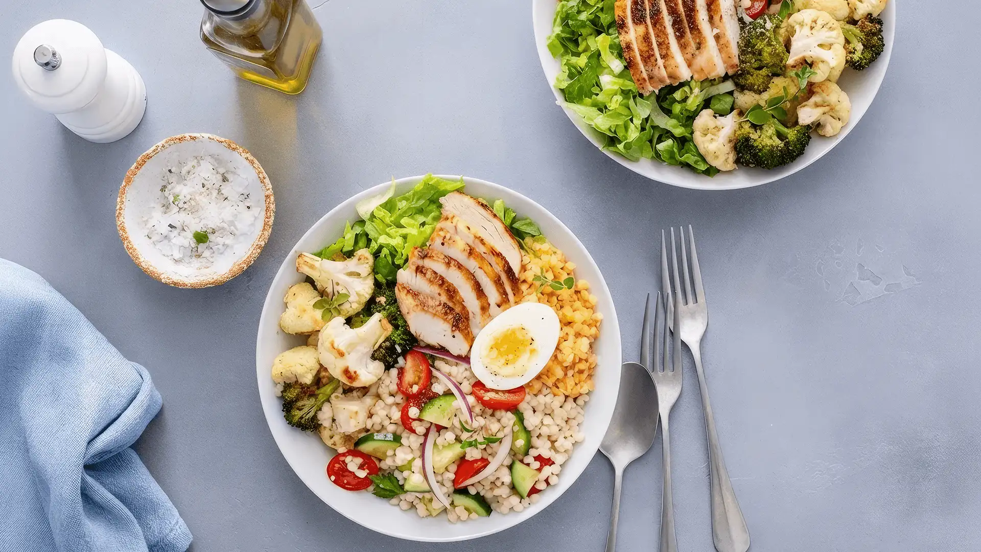 Bol-repas sain avec poulet grillé, légumes rôtis, laitue fraîche, lentilles cuites, salade de couscous et œuf cuit dur