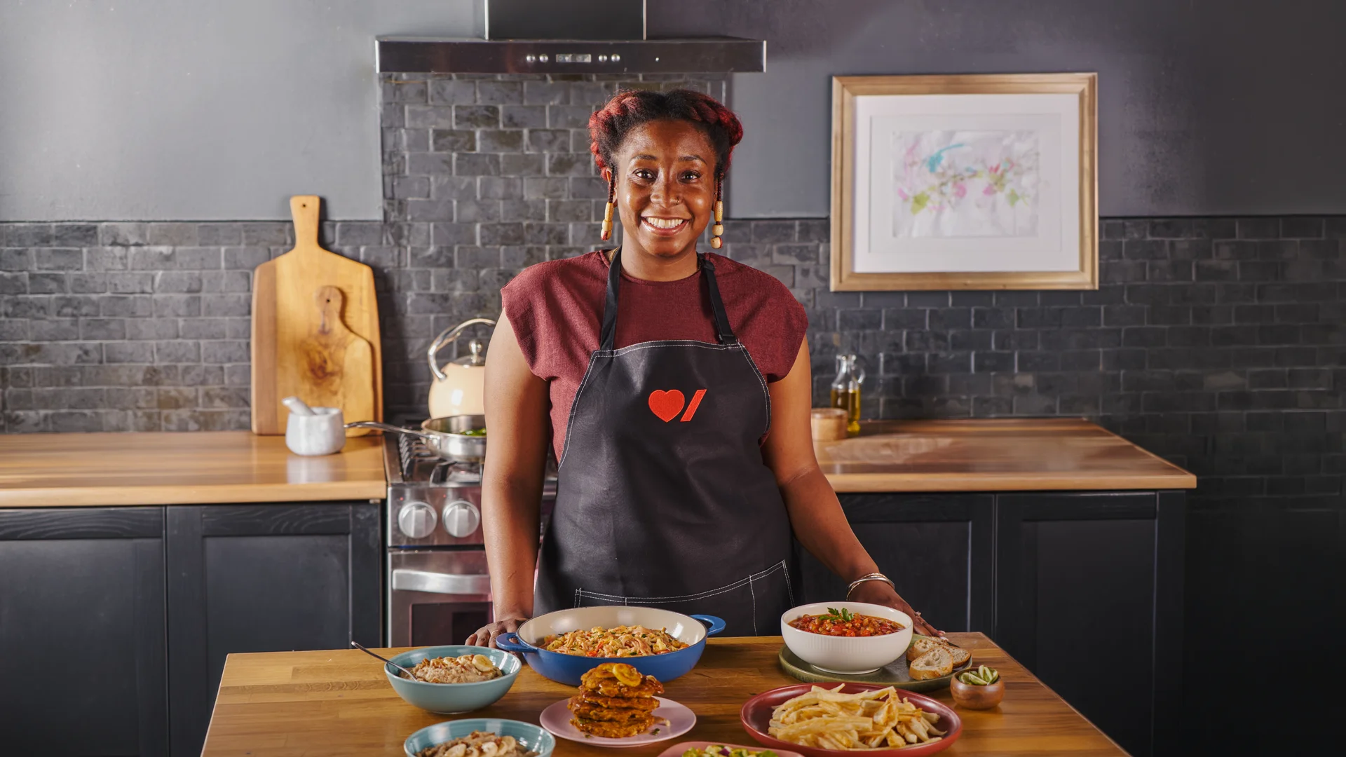 Une femme coupe un oignon rouge sur un comptoir de cuisine où sont disposés des légumes frais.