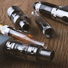 Cinq vapoteuses sur une table. 