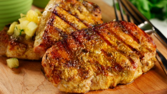 Gros plan des côtelettes de porc grillées sur une planche à découper l' ananas