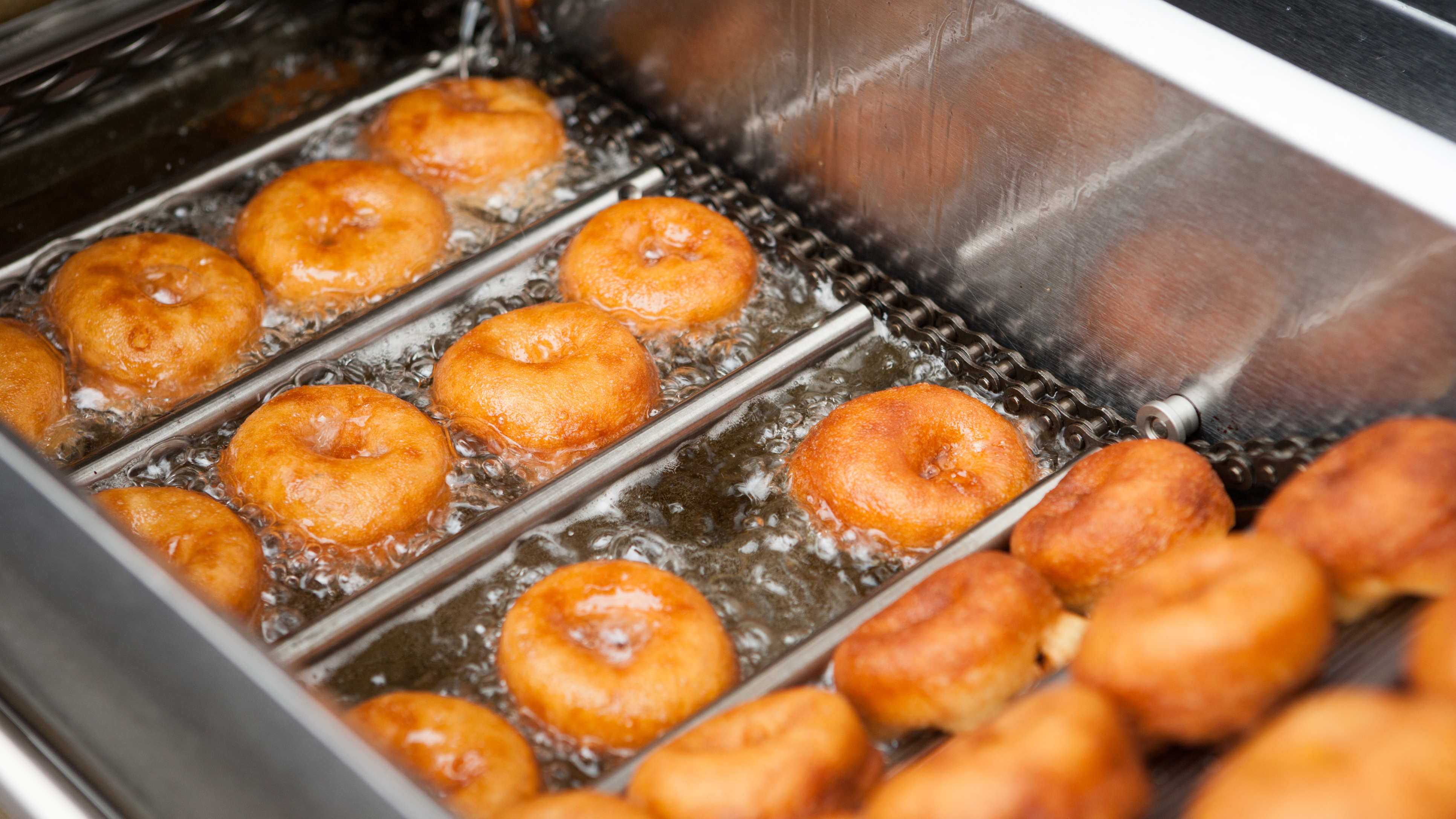 Une douzaine de beignes en train de frire dans l’huile.