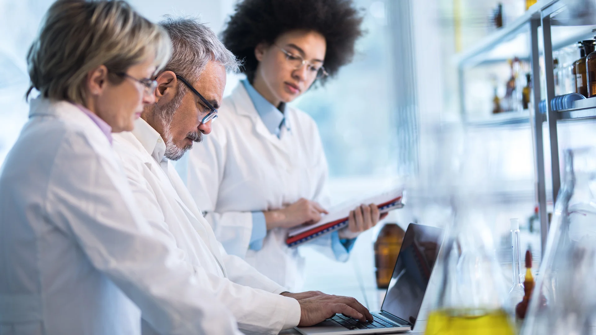 Trois scientifiques utilisent un ordinateur dans un laboratoire.