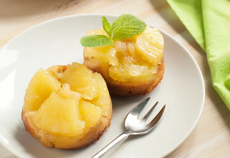 Deux gâteaux de quinoa à l'ananas sur une assiette blanche avec une fourchette.