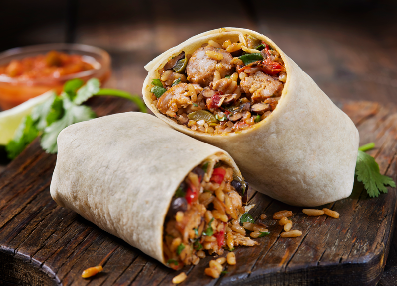 Un burrito coupé en deux sur une planche en bois.