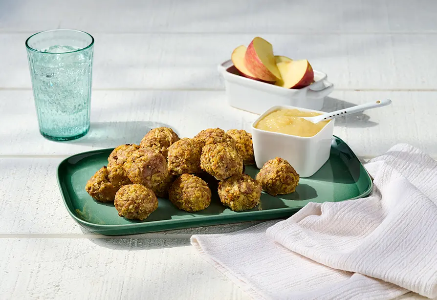 Trois boulettes de dinde aux pommes avec de la compote de pommes, dans une assiette.