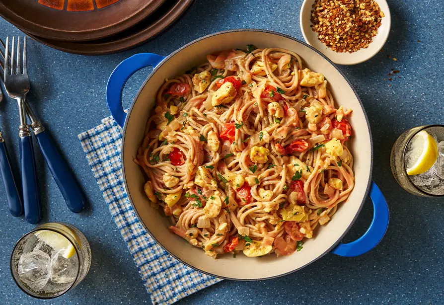 Spaghettis à l’akée servis dans un bol en grès à poignées bleues