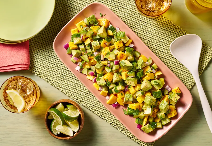 Salade de mangues, d’avocat, de concombre et d’oignon dans un plat de service rose. 