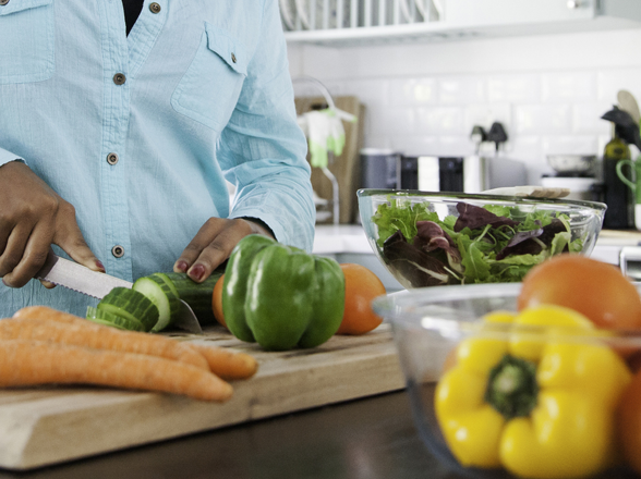 Une personne coupe des légumes dans une cuisine