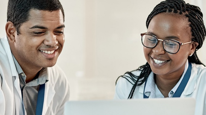 Deux universitaires noirs, un homme et une femme, regardent ensemble un écran d’ordinateur.