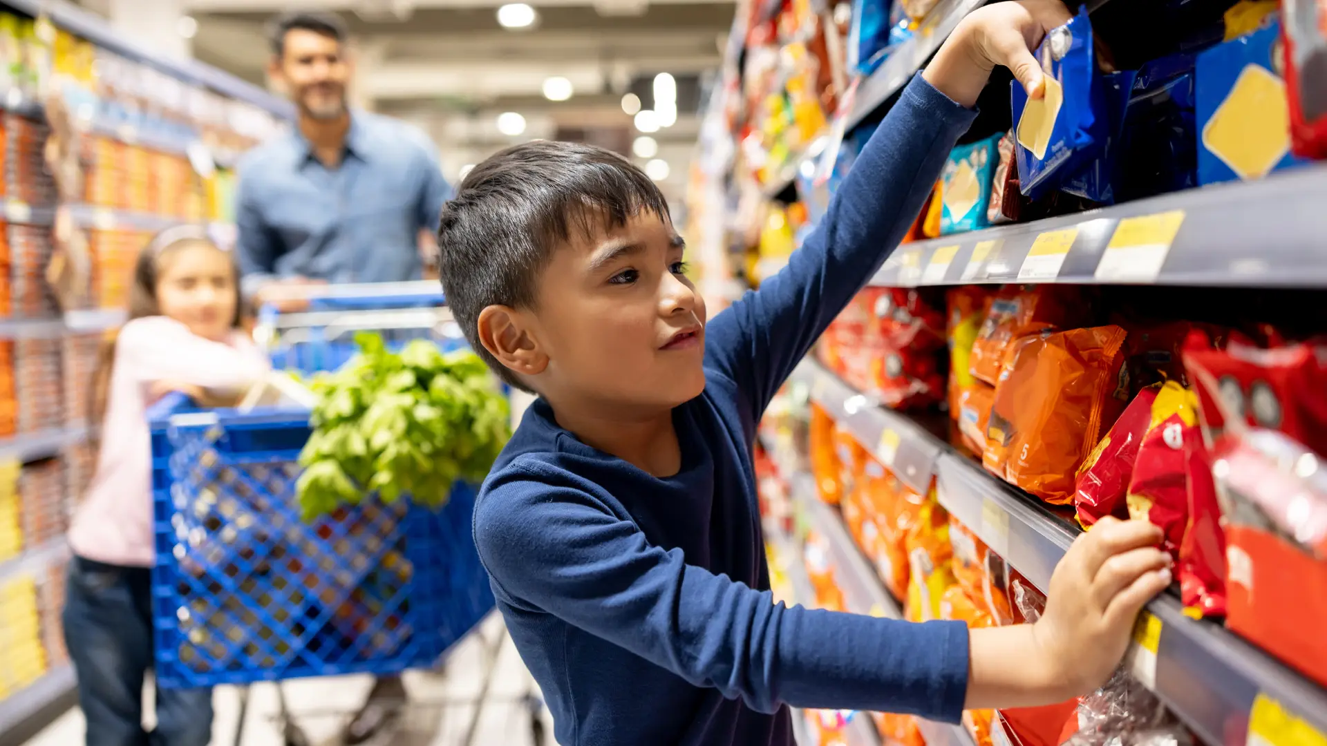 Un jeune garçon choisit des articles sur une étagère à l’épicerie.