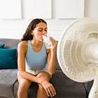 Une femme se rafraîchissant devant un ventilateur avec de l’eau glacée