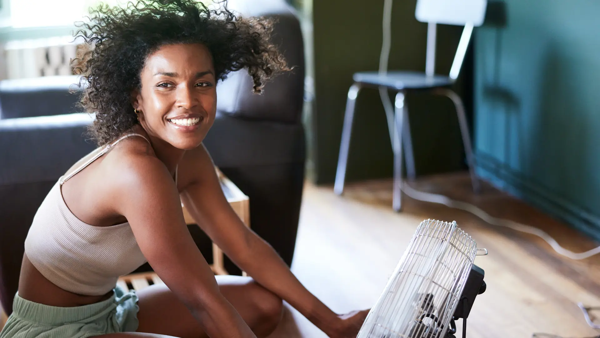 Une femme assise à l’intérieur, devant un ventilateur