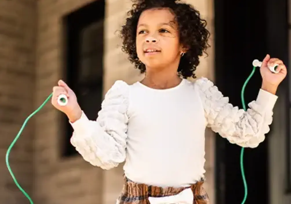 Nora saute à la corde près de sa maison.