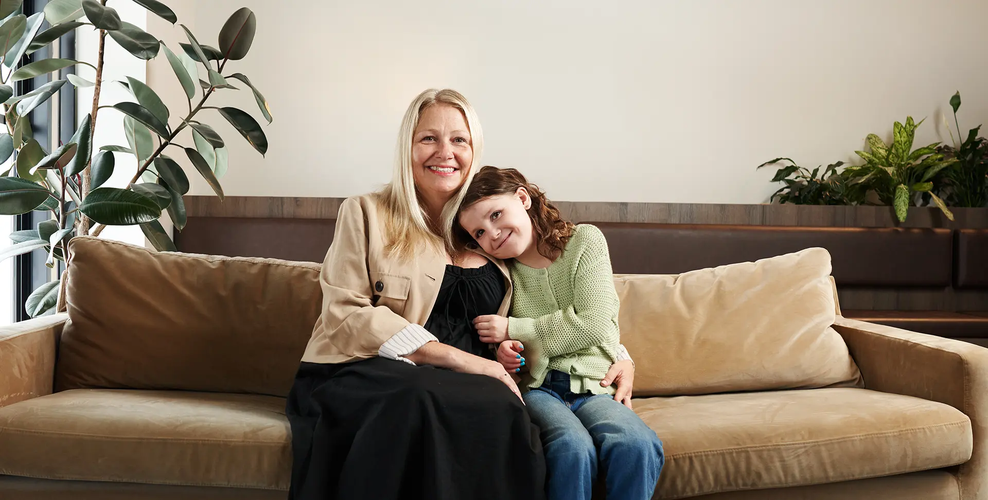 Natalie assise sur le canapé se blottissant contre sa mère.