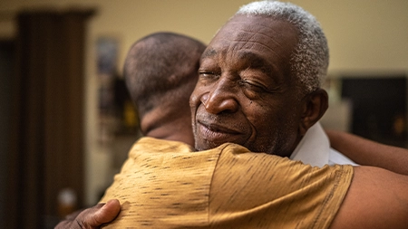 Two people embracing warmly, one with a peaceful expression and closed eyes.