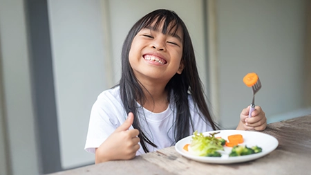 Une jeune fille souriante déguste un repas équilibré.