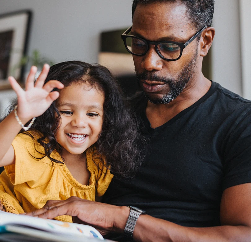 Un homme assis avec sa jeune fille lisant un livre.