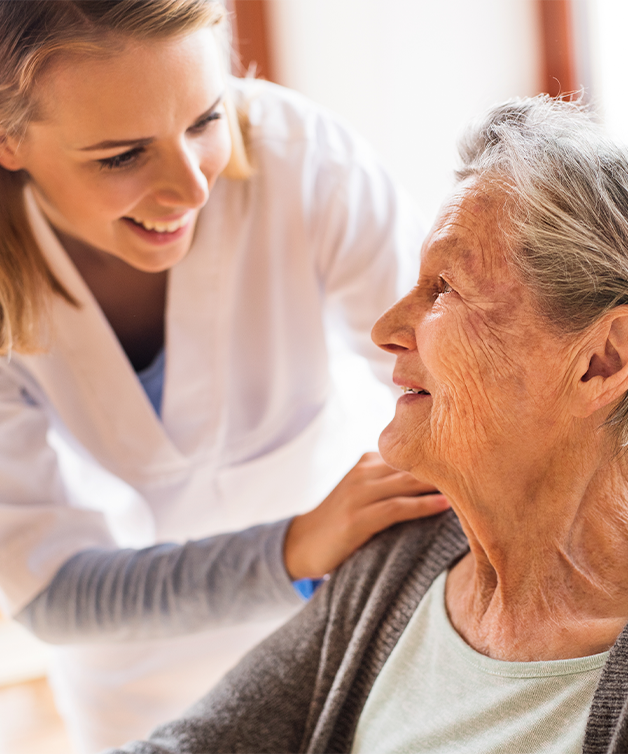 Une infirmière discute avec une personne âgée en fauteuil roulant.