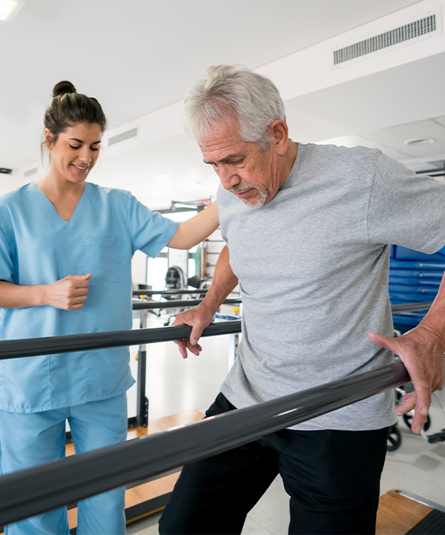 Un homme âgé fait des exercices de réadaptation après un AVC avec le soutien d’une infirmière.