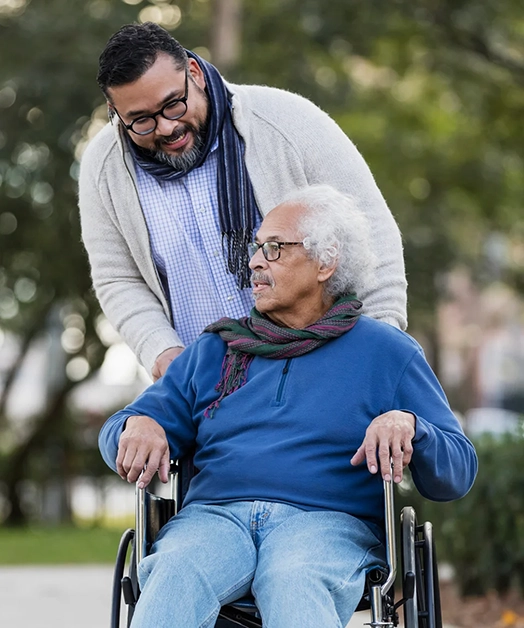 Un homme âgé en fauteuil roulant discutant avec son soignant.