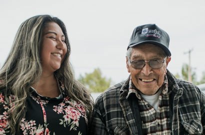 Une jeune femme sourit à un homme âgé portant une casquette.
