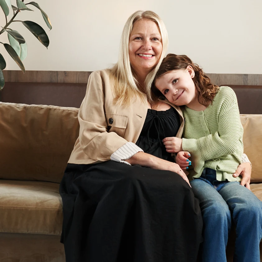Natalie, une enfant qui vit avec une maladie du cœur, est assise avec sa mère sur un canapé. 