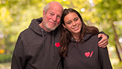 Un père avec son bras autour de sa fille, tous deux portant des sweats à capuche de la marque Cœur + AVC.
