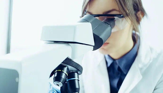 Une chercheuse regarde dans un microscope
