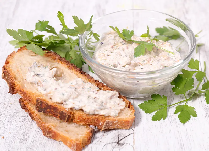 Tartinade de haricots blancs au fromage de chèvre et à la menthe dans un bol en verre accompagnée de pain grillé.