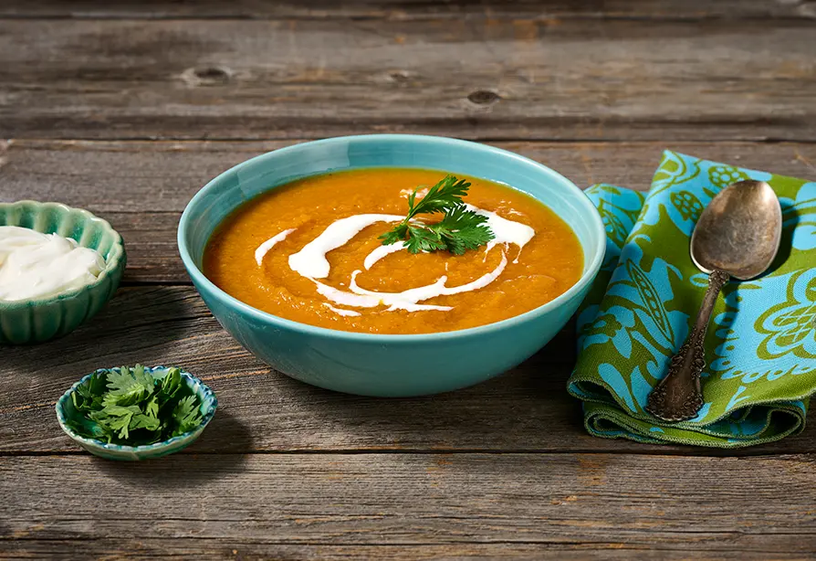 Soupe aux carottes et à la courge garnie de yogourt et de coriandre