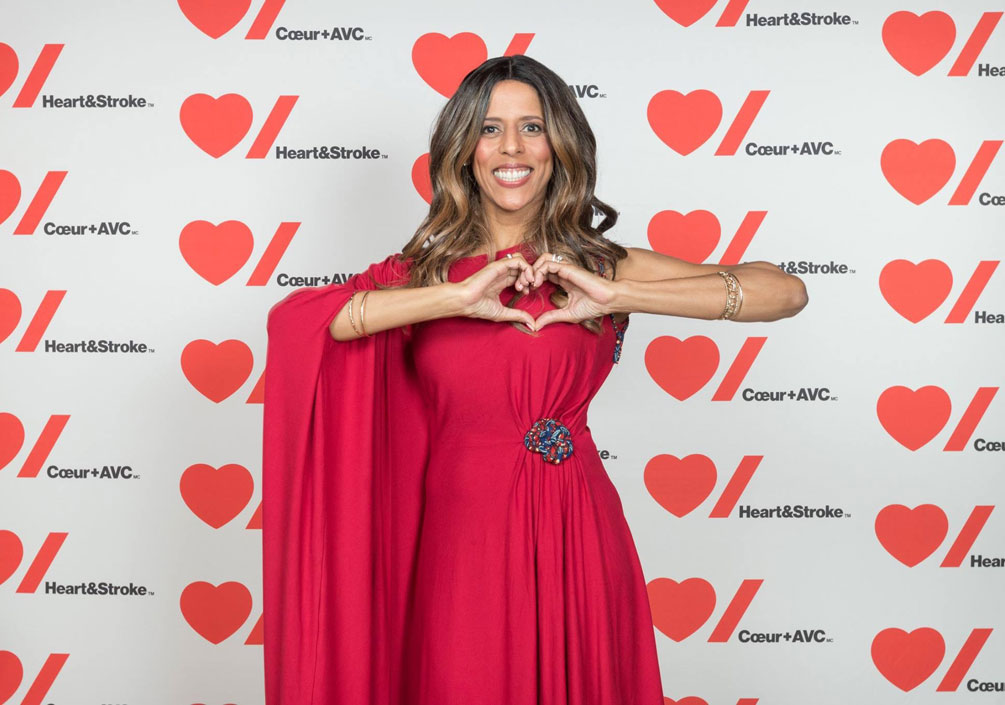  Caroline Lavallée porte une robe rouge et tient ses mains en forme de cœur.