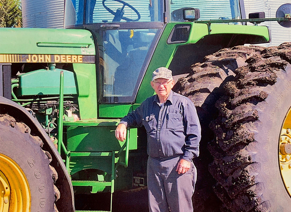 Barrie Clayton se tient à côté d’un tracteur