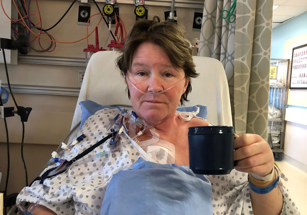 Heather Evans tient une tasse de thé dans son lit d’hôpital