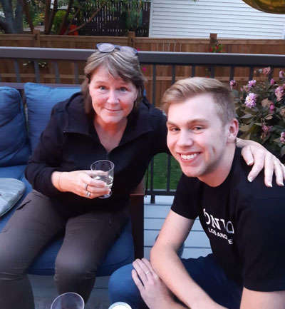 Heather avec son bras autour de son fils Skyler assis sur un porche avec un verre à la main.