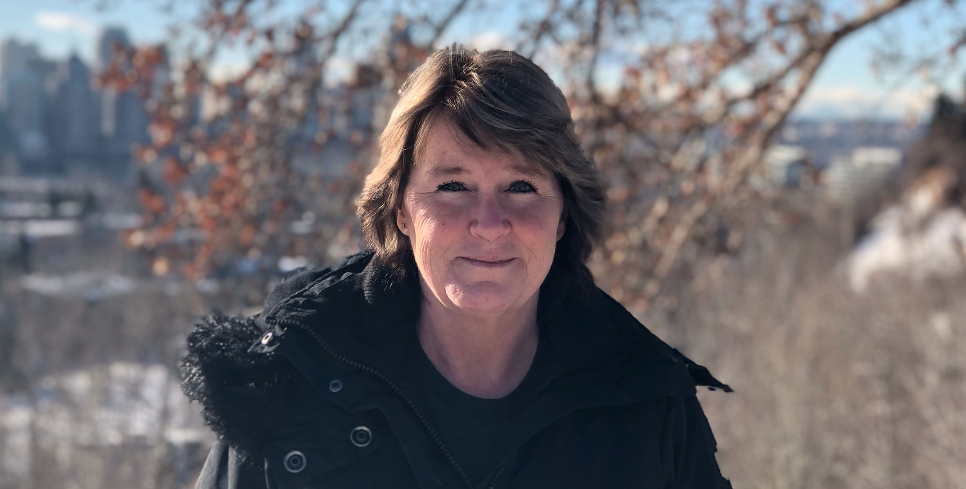 Heather Evans souriant à l'extérieur par une journée ensoleillée avec un paysage urbain au loin