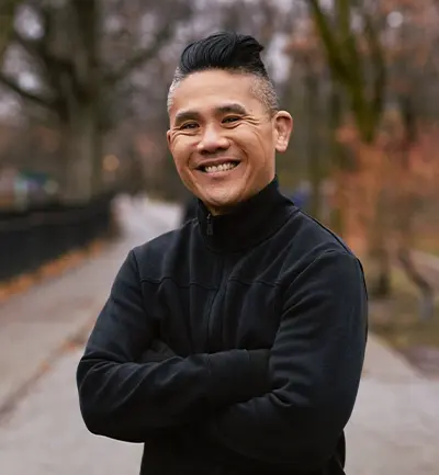 Ken Wong sourit, les bras croisés.