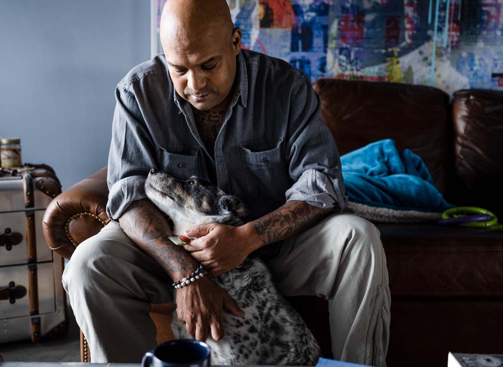 Kevin assis sur un sofa caressant son chien.