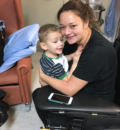 Megan est assise dans un fauteuil roulant à l’hôpital avec son fils, Lucas.