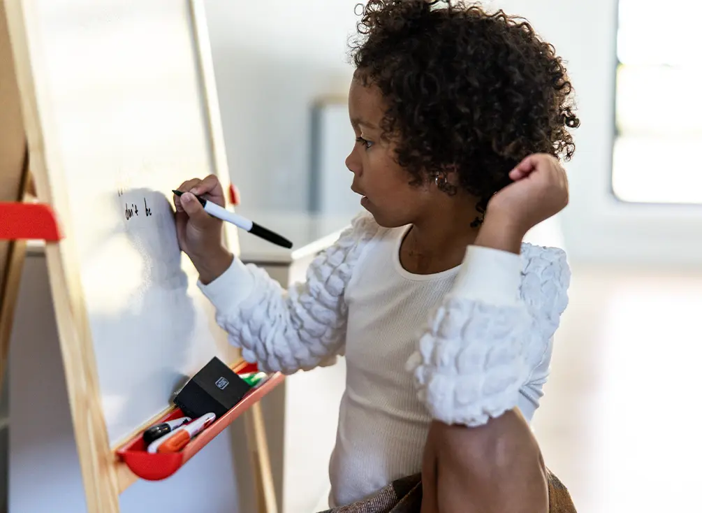 Nora Evelyn écrit sur un tableau blanc.
