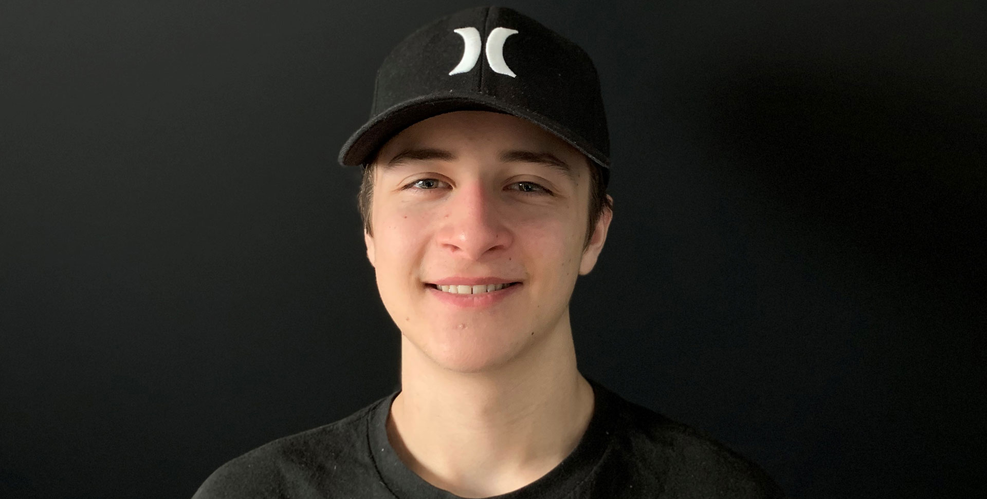 Olivier Lanthier sourit dans un haut sombre et une casquette de baseball