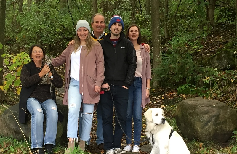 Paul King, tout souriant, est avec sa femme et ses trois enfants adultes en forêt.